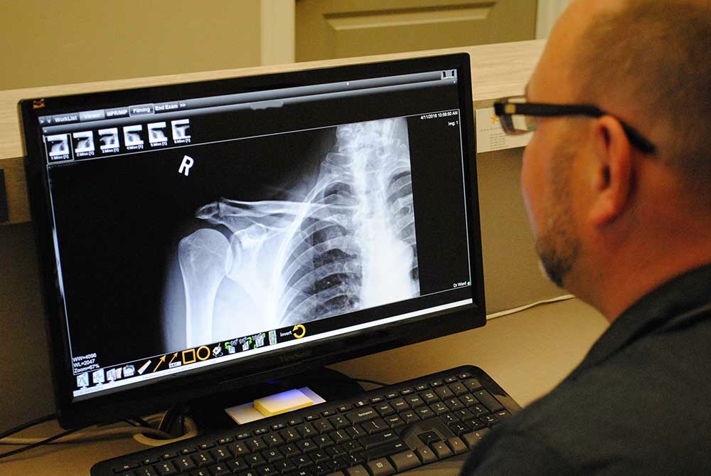 dr ward examining x-ray on a computer screen.